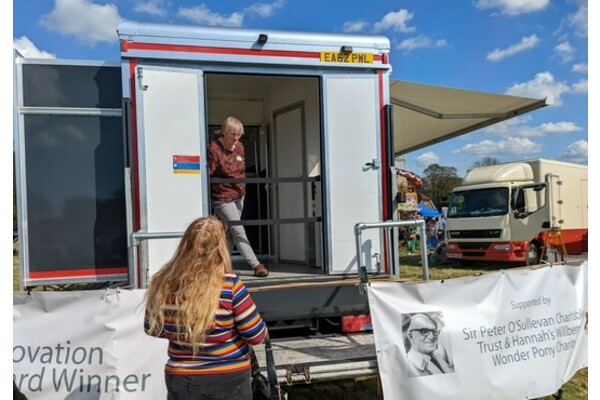 A brightly dressed person chatting to us in the Horsebox at Lambourn Show last year. With a banner of Sir Peter O'Sullevan on view too. We hope the sun shines again! 