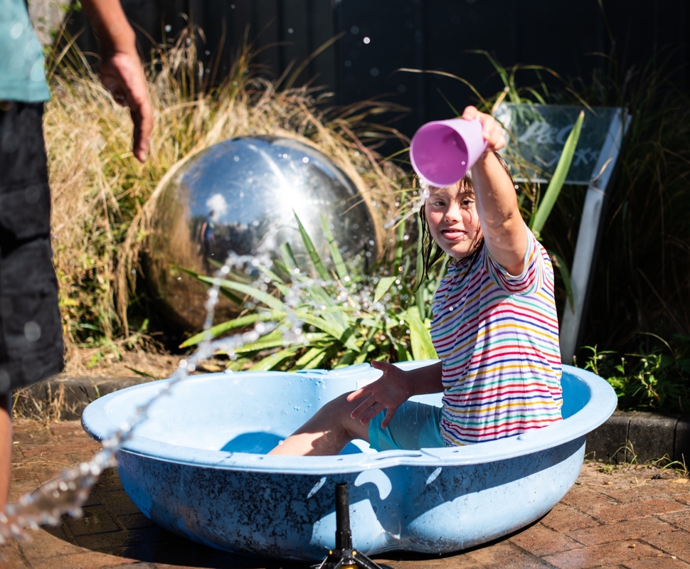 A young girl playing in a paddling pool n a sunny day