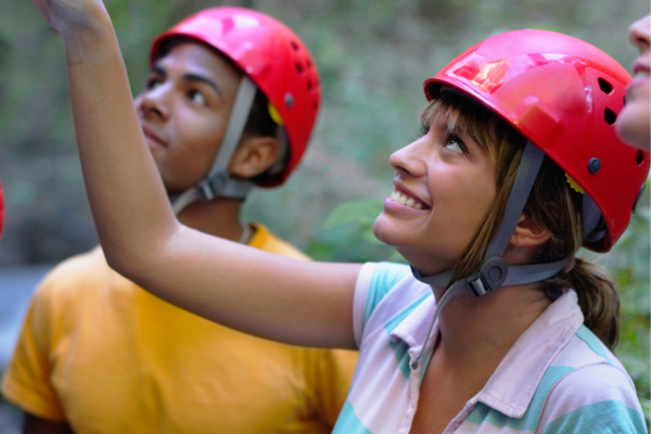 Two people wearing helmets, they are looking up and smiling. 