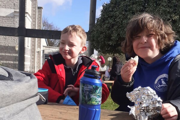 Two young boys enjoying sandwhiches in the park 