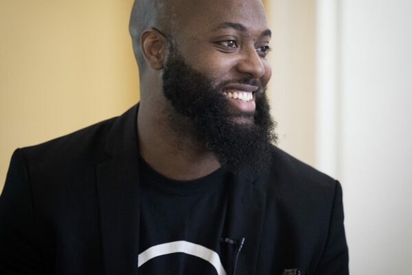 Image of bearded man look to his left and smiling.