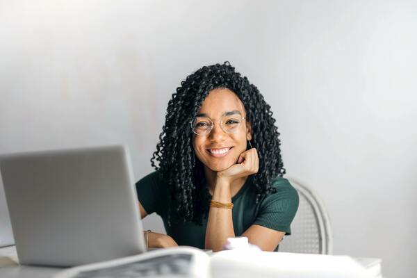 Young person smiling at a laptop (Image by Andrea Piacquadio from Pexels)
