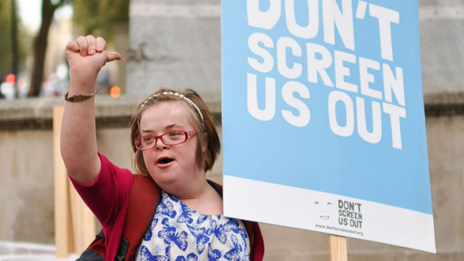 A woman with Down's Syndrome protesting by holding a placard in the street