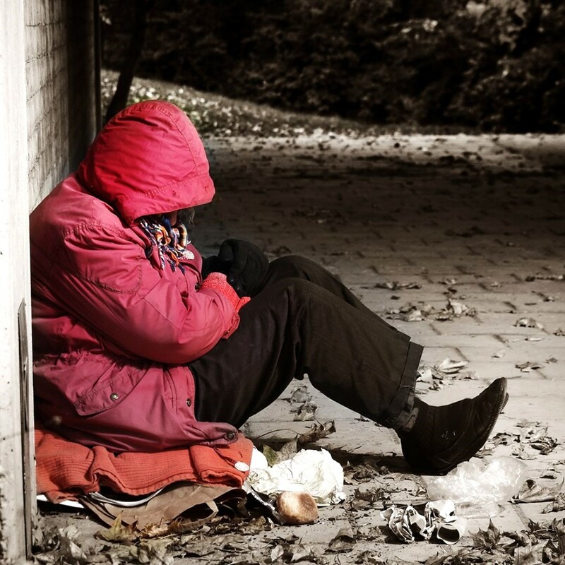Homeless man sitting on a pavement