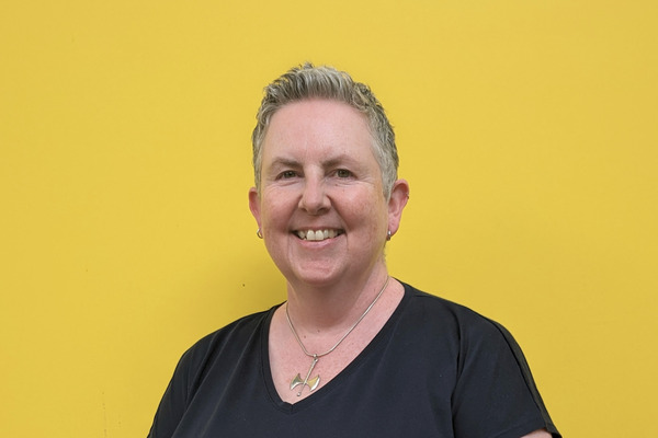 An image of Jo Todd, CEO at Respect, wearing a black tshirt against a yellow background