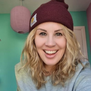 A photo of Amy. She has blonde hair and is wearing a beanie hat.