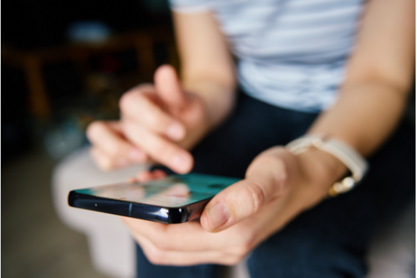 Stock photo of a person scrolling on a mobile phone.