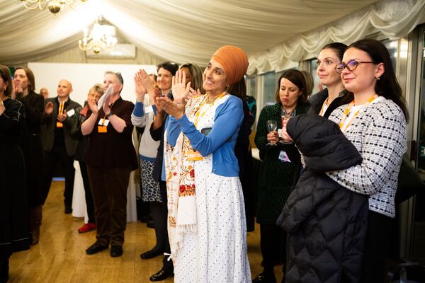 A group of women smiling and clapping at Respect's 25th anniversary event.