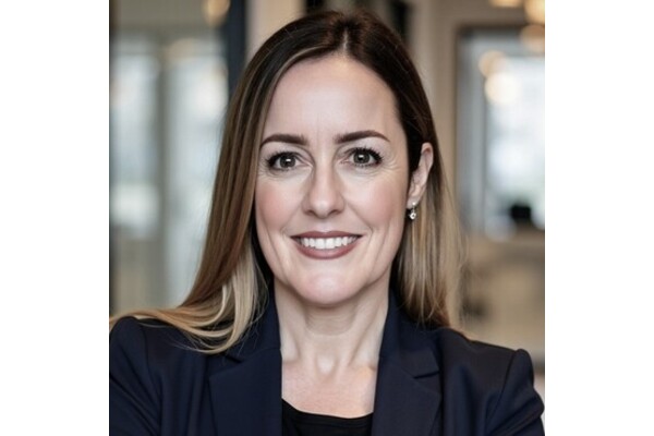 A photo of Kate Bohn. She has blonde hair and is wearing a suit jacket and smiling at the camera.