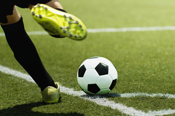 Image of person kicking football across the line