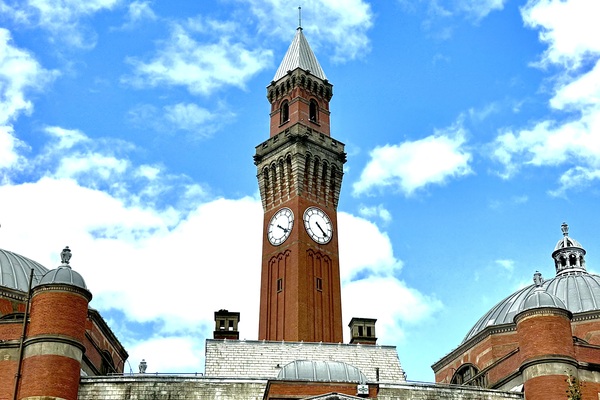 Image of the clock tower from University of Birmingham campus, with a bright blue sky and some clouds behind it