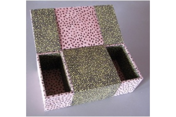 Photo of a box with three compartments, covered in alternating green and pink decorated paper. The outer two compartments are open, with the centre still closed.