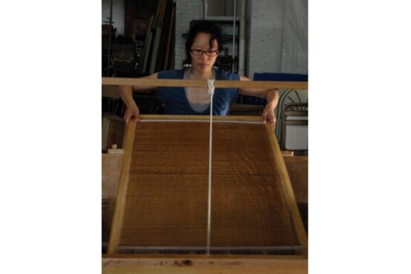 Photo of Lee guiding a large suspended mould and deckle