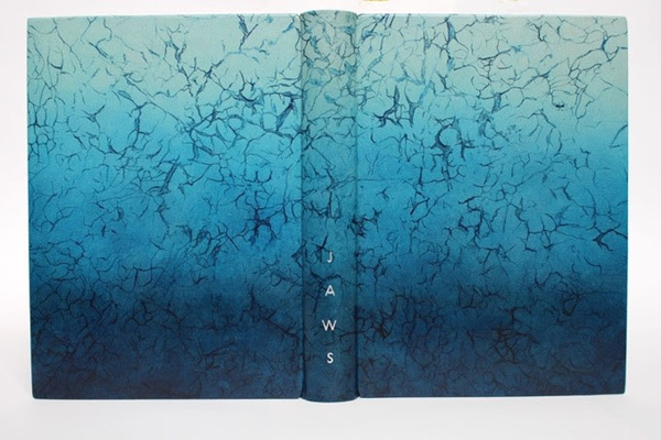 Photo of a fine binding in leather dyed a textured grey to dark blue gradient, with red to white gradient painted edges with palladium flakes