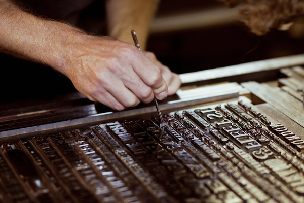 Setting a broadside of metal type samples with tweezers