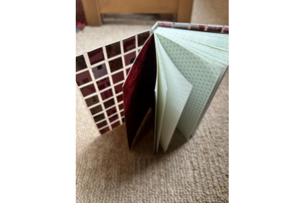 A sketchbook with hex graph paper and clear laminated boards with small square sections of cereal packet  