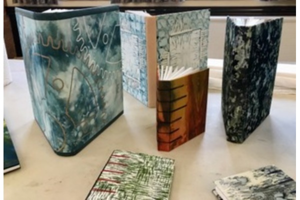 An array bindings in hand-coloured bookcloth with screen printing