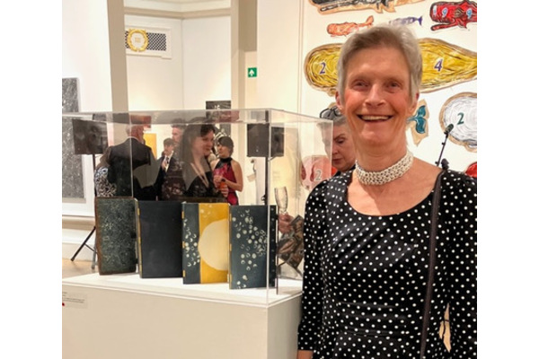 Susie standing next to a display case of her bindings.