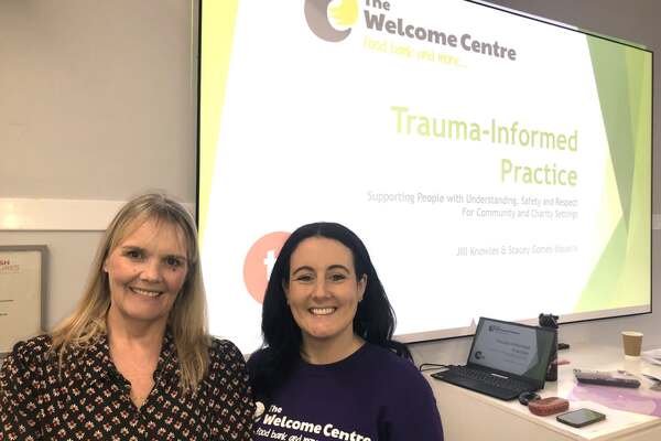 Photo of Deputy Chief Executive, Jill Knowles and Advice, Guidance and Support Service Manager, Stacey Gomes-Siqueira next to powerpoint presenation