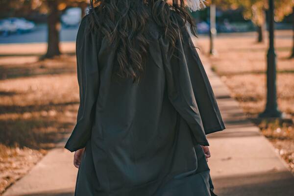 Woman in Black Long Sleeve Dress Standing on Brown Concrete Pathway