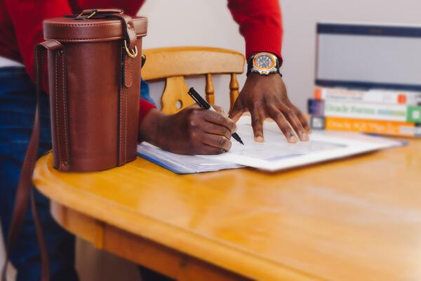 Hand using a pen writing on a paper document. 