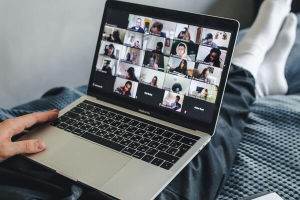 A-person-sitting-on-the-bed watching a meeting on their laptop