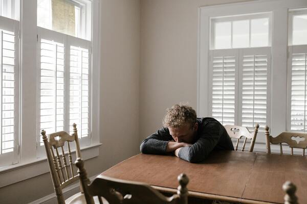 Man in grey sitting on brown wooden chair