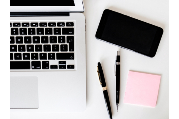 laptop, two pens, post it notes and mobile phone