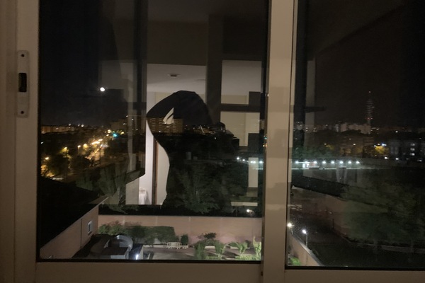 Photo of Evie's reflection in a window with a backdrop of city lights